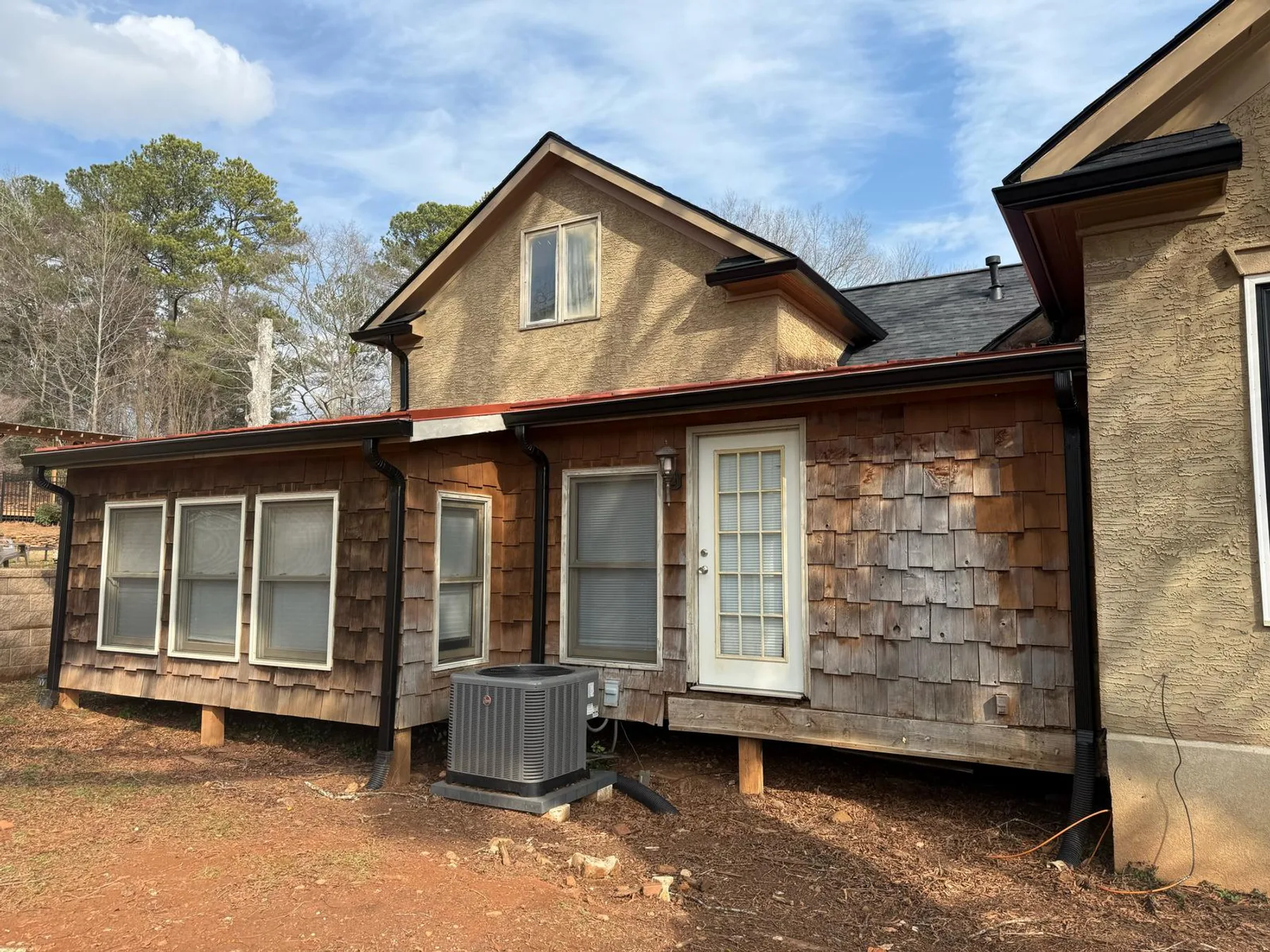Seamless gutters and downspout installed on a cedar shake home addition