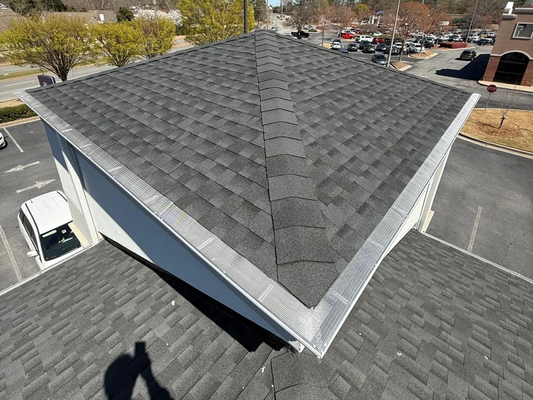 Aerial view of gutter guard mesh installed along a commercial roofline