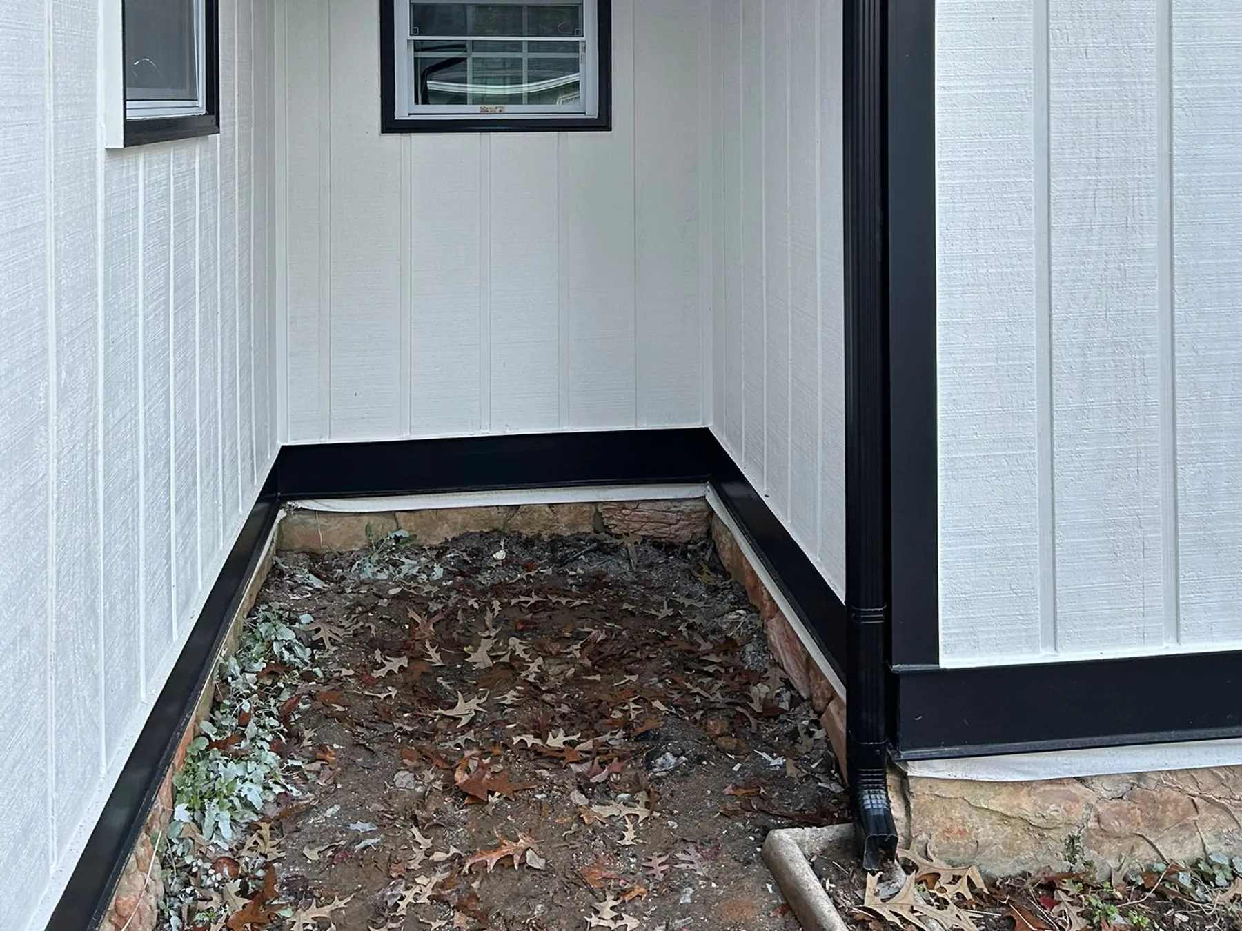 Close-up of dark-trim gutter and downspout on a home remodel