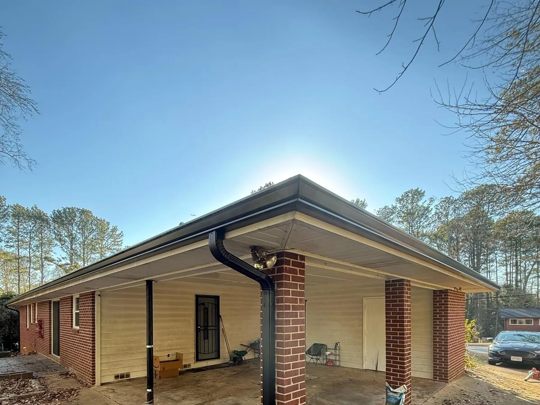 Gutter downspout installed along a brick carport